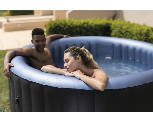 Uppblåsbar bubbelpool med två personer i trädgården.