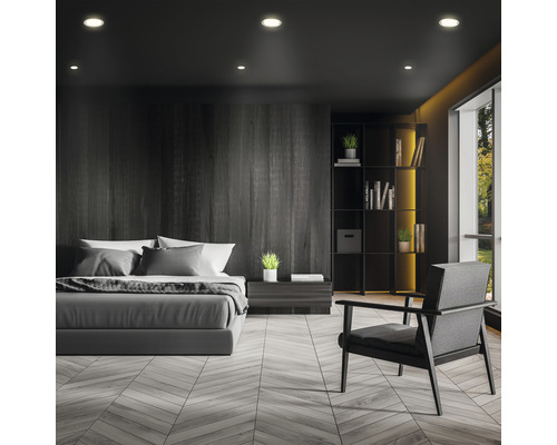 Sovrum med säng, fåtölj och bokhylla i mörk design