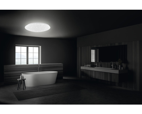 Modernt badrum med fristående badkar, tvättställ och rund taklampa