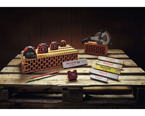 Murarverktygssortiment på träpall med måttband, mäthjul, tumstockar, pennor och digital klocka