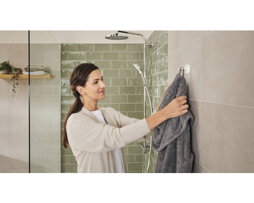 Kvinna hänger badrock i badrummet på en krok bredvid duschen