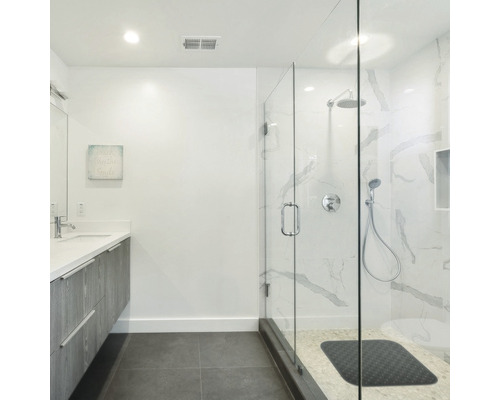 Ljust badrum med handfat, spegel och duschkabin i glas