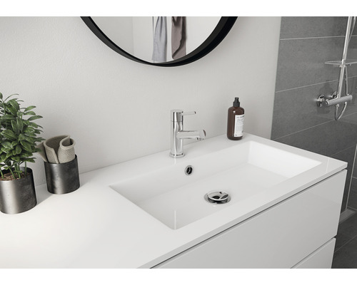 Ljust badrum med handfat, blandare och spegel