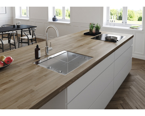 Köksö med diskho, armatur, spishäll och bänkskiva i trä i ett ljust kök