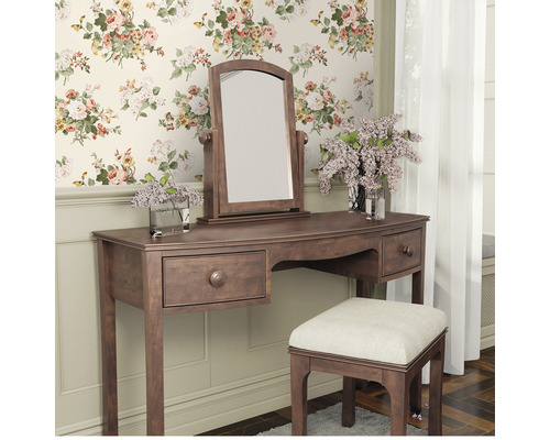 Sminkbord med spegel och pall framför en blommig tapet