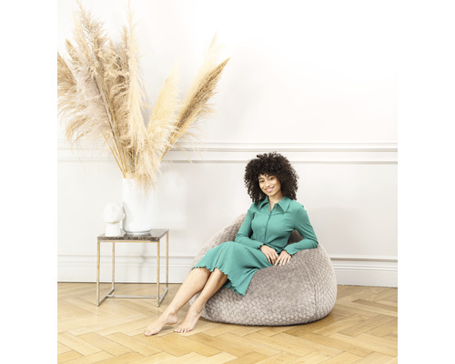Kvinna sitter på en grå sittsäck i ett vardagsrum