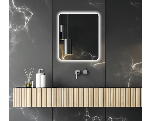 Modernt badrum med belyst spegel, tvättställ och armaturer mot en mörk bakgrund