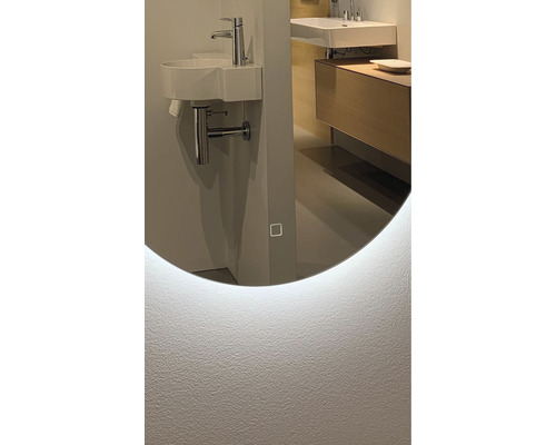 Detaljvy av ett badrum med en rund spegel med LED-belysning, handfat och blandare