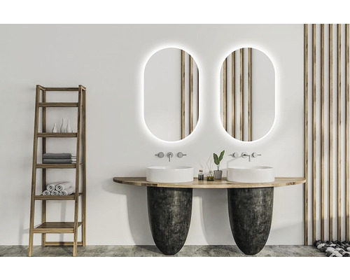 Ljust badrum med två handfat, speglar med belysning och trälhylla