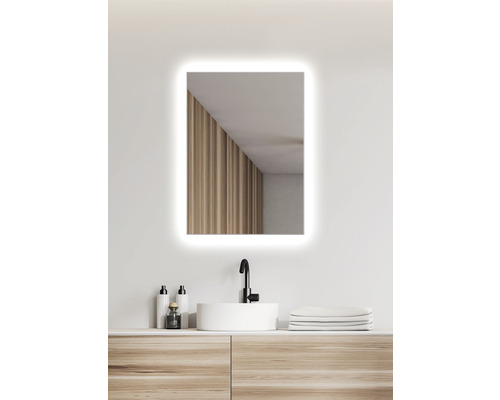 Belyst rektangulär badrumsspegel ovanför ett tvättställ med bänkskiva.