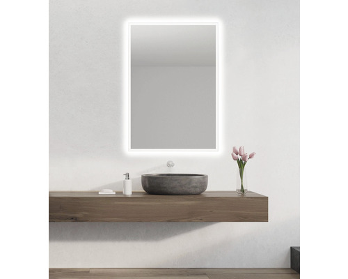 Badrum med belyst spegel, tvättställsskåp och tvättställ ovanpå bänken.