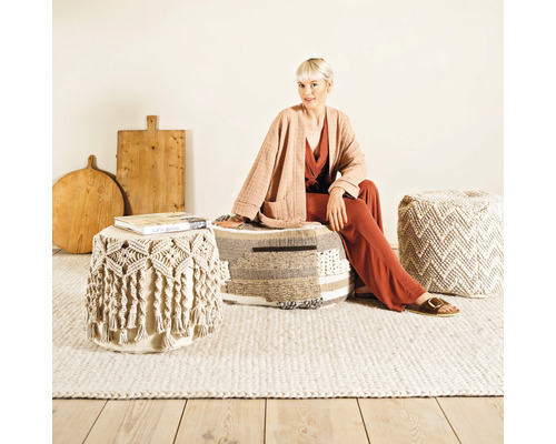 Vardagsrumsscen med kvinna sittande på en puff, andra puffar och träfat i bakgrunden