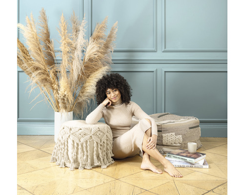 Dekorativ scen med kvinna, prydnadsgräs och puff på trägolv