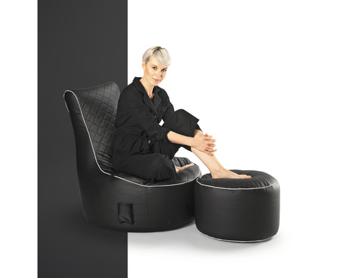 Kvinna sitter i en svart fåtölj med fotpall