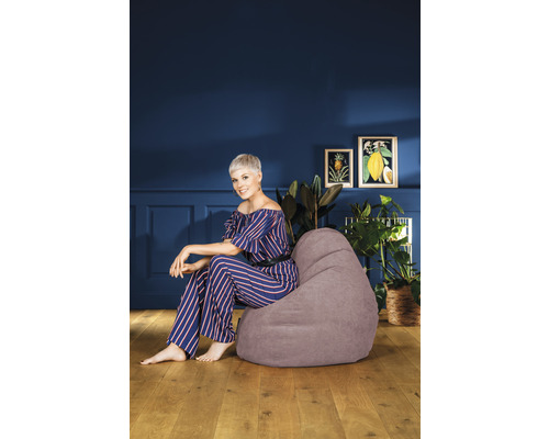 Kvinna sitter på en grå sittsäck i ett vardagsrum.