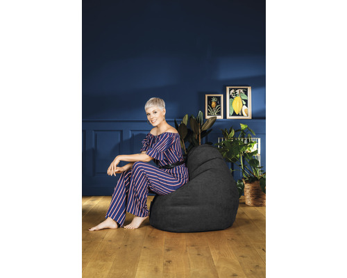 Kvinna sitter på en svart sittsäck i ett rum med växter och dekoration