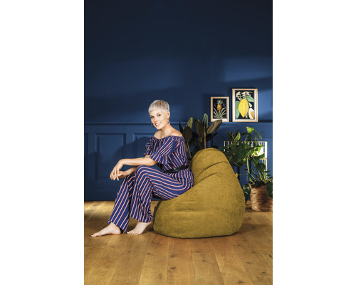 Kvinna sitter på en grön sittsäck i ett rum med dekoration