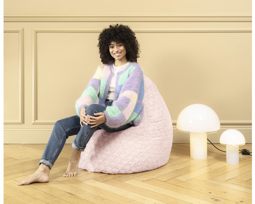 Kvinna sitter på en rosa sittsäck, bredvid den två svamplampor