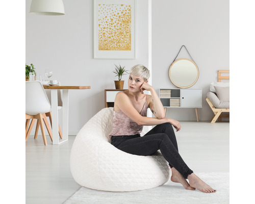 En kvinna sitter på en vit sittsäck i ett ljust vardagsrum.
