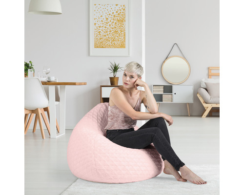 Kvinna sitter på en rosa sittsäck i ett ljust vardagsrum.