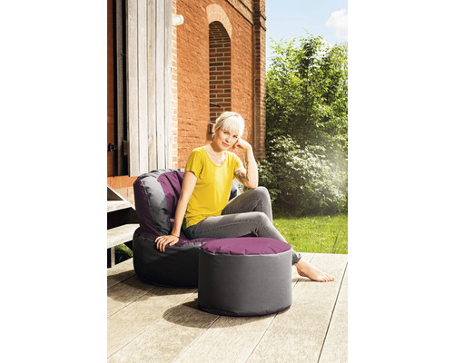 Kvinna sitter utomhus på en sittsäck med fotpall