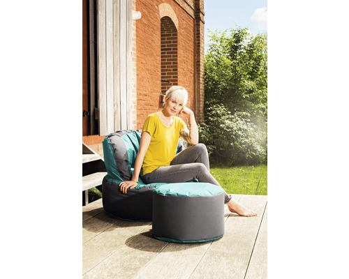 Kvinna sitter på sittsäck med pall i trädgården.