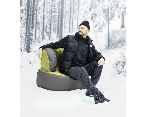 Man sitter i en fåtölj i snön framför en suddig skog