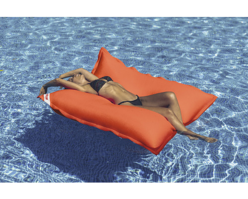 Kvinna kopplar av på en orange poolö i poolen