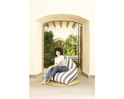 Kvinna sitter på en randig sittsäck på en flätad matta