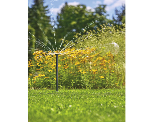 Trädgårdsscen med en grässpridare som sprutar vatten