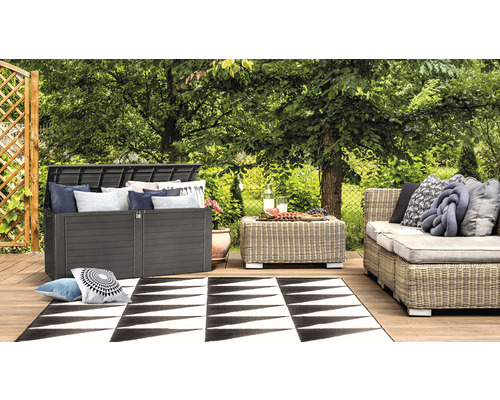 Trädgårdsscen med en dynbox, ett bord, en soffa och en matta på en träaltan