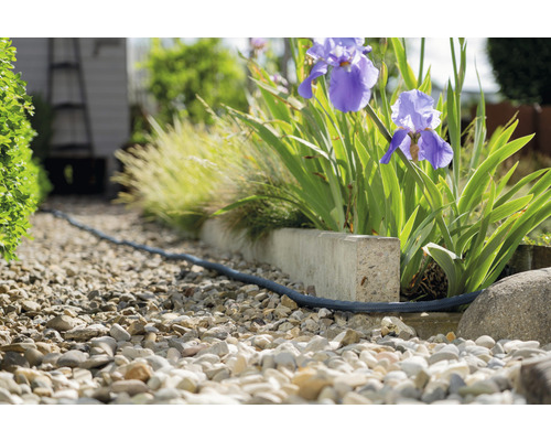 Trädgårdsgång med grus och en flexibel bevattningsslang