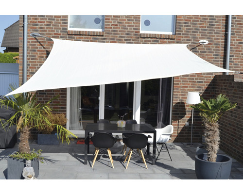 Vitt solsegel över en terrass med bord och stolar