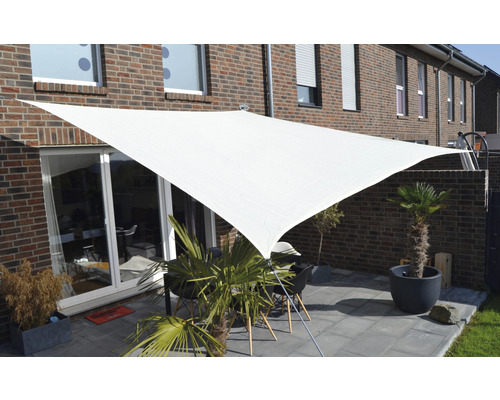 Terrass med triangelformat solskydd och trädgårdsmöbler framför ett tegelhus