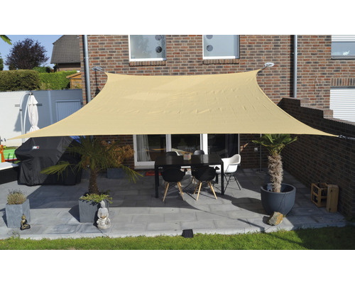 Terrass med solsegel, bord och stolar framför ett hus