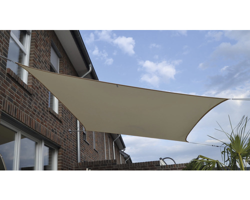 Beige solsegel på en tegelbyggnad med blå himmel