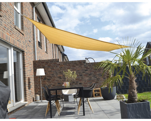 Uteplats med solsegel, bord och stolar framför ett hus