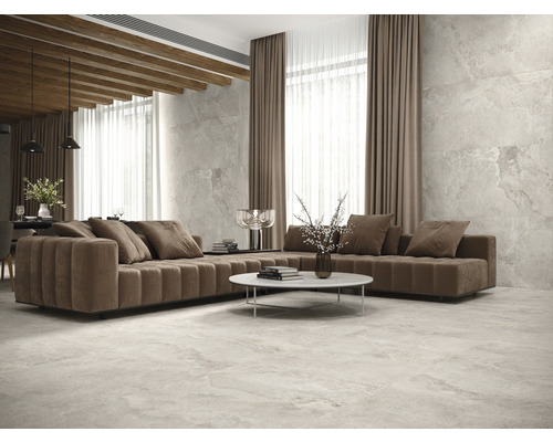 Vardagsrum med soffa, bord och klinkergolv.