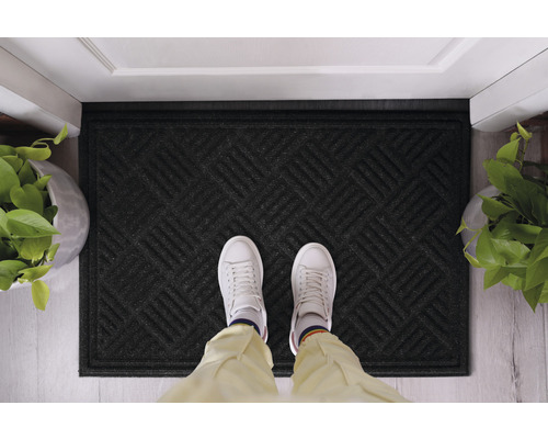 Svart dörrmatta med geometriskt mönster framför en dörr