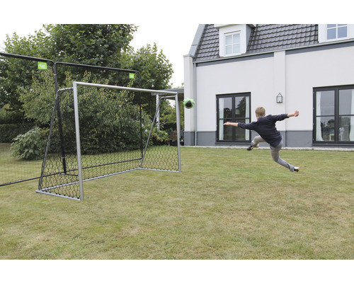 Fotbollsmål med fotboll på gräs och person som skjuter