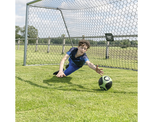 Pojke håller en fotboll framför ett fotbollsmål.