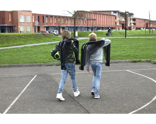 Två barn bär ihopvikta vagnar på en skolgård.