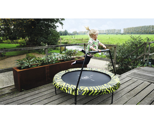 Flicka hoppar på en EXIT Toys-studsmatta med handtag i trädgården