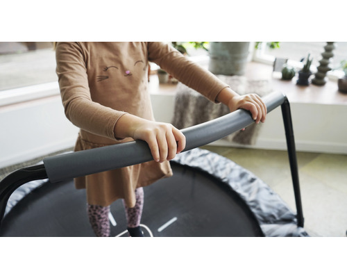 Barn håller i sig i en rund, grå barntrampolin