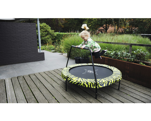 Barn hoppar på en trädgårdstrampolin med handtag.