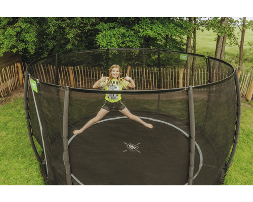 Flicka hoppar på en trädgårdstrampolin med säkerhetsnät