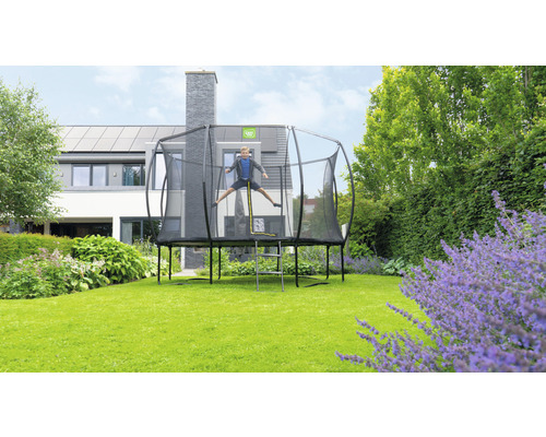 Trampolin med säkerhetsnät och hoppande barn i trädgården