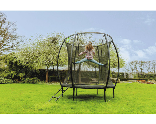 Ett barn hoppar på en trädgårdstrampolin med säkerhetsnät och stege