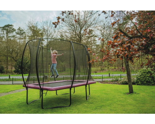 Flicka hoppar på en studsmatta med skyddsnät