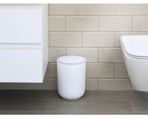 Scen av ett badrum med en vit kosmetikahink med lock